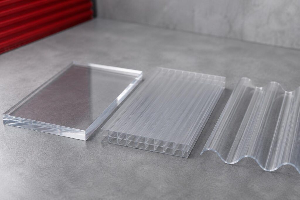 Clear solid, multiwall, and corrugated polycarbonate sheet samples on a concrete surface