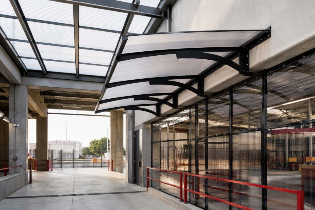 Polycarbonate canopy and wall panels installed on a commercial building façade