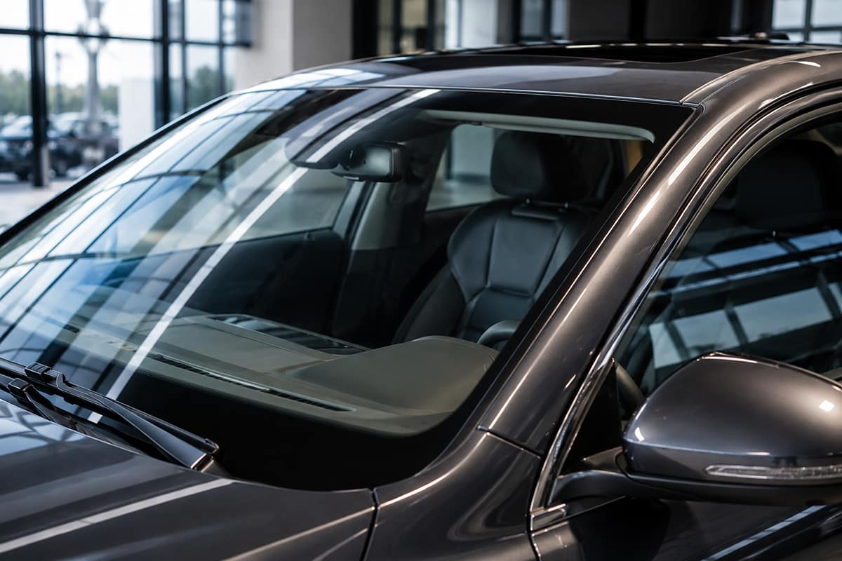 Close-up of a modern vehicle windshield and side window showing clear automotive glazing in a showroom
