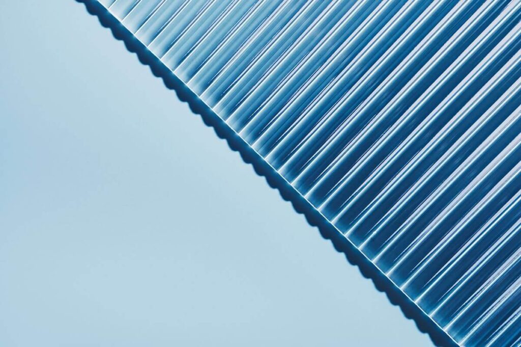 Close-up of a clear corrugated polycarbonate sheet showing its lightweight structure and transparent ribbed surface