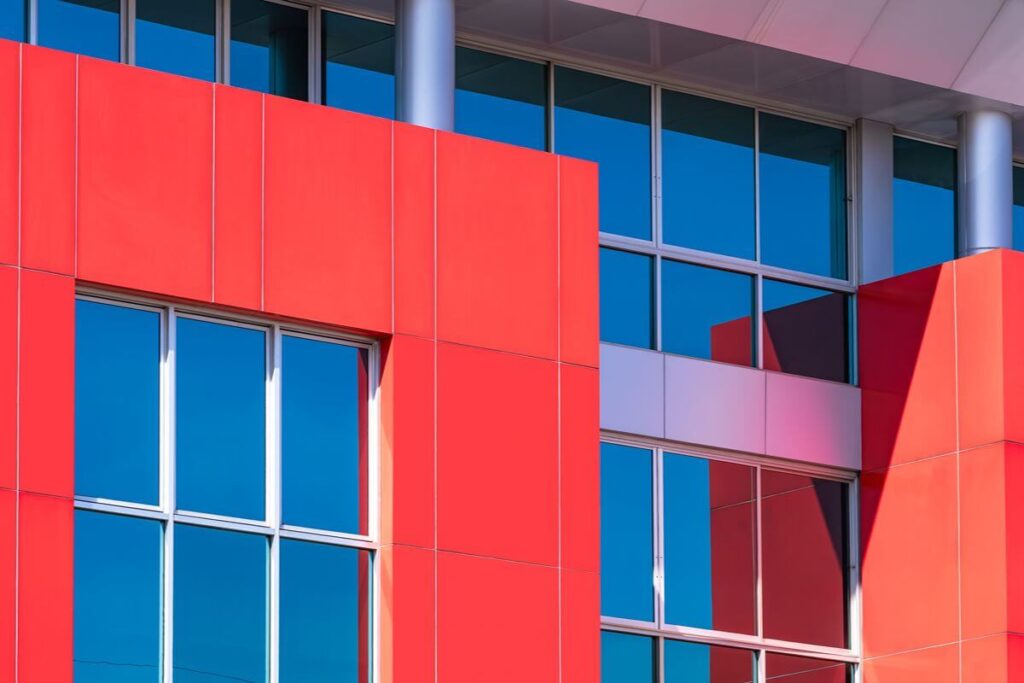 Commercial building facade with bright red architectural panels framing large blue-tinted windows