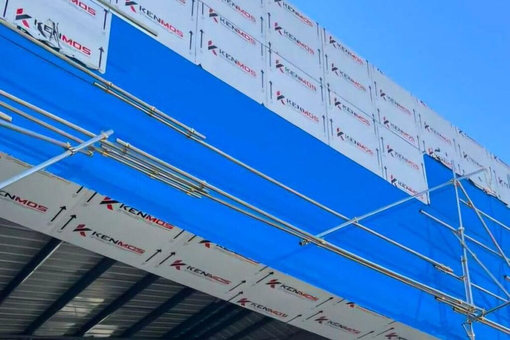 KENMOS architectural panels being installed on a commercial building facade using exterior scaffolding